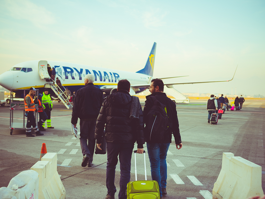 Back view of people carrying luggage boarding on a Ryanair plane